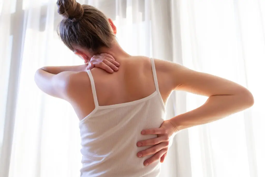 woman grabbing her back shoulder due to muscle soreness
