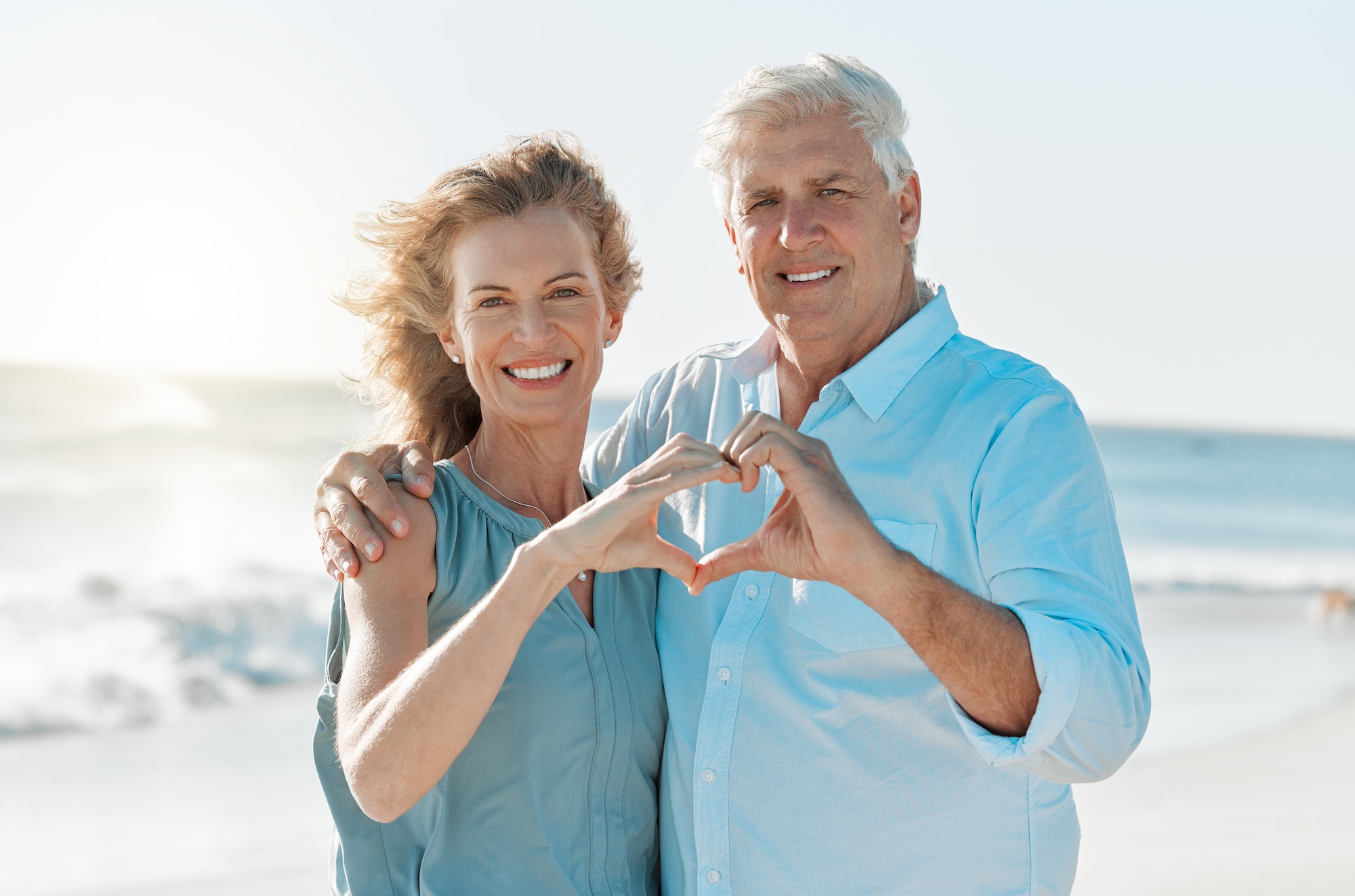 Shot of a mature couple forming a heart with their hands while at the beach