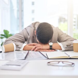 Tired business man sleeping at desk with burnout, stress problem and low energy in office. Fatigue,