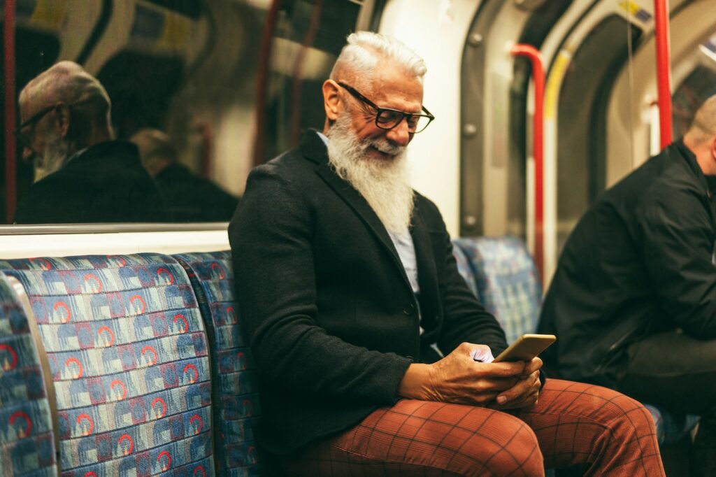 Senior hipster man using smartphone in subway underground - Focus on hands holding mobile phone