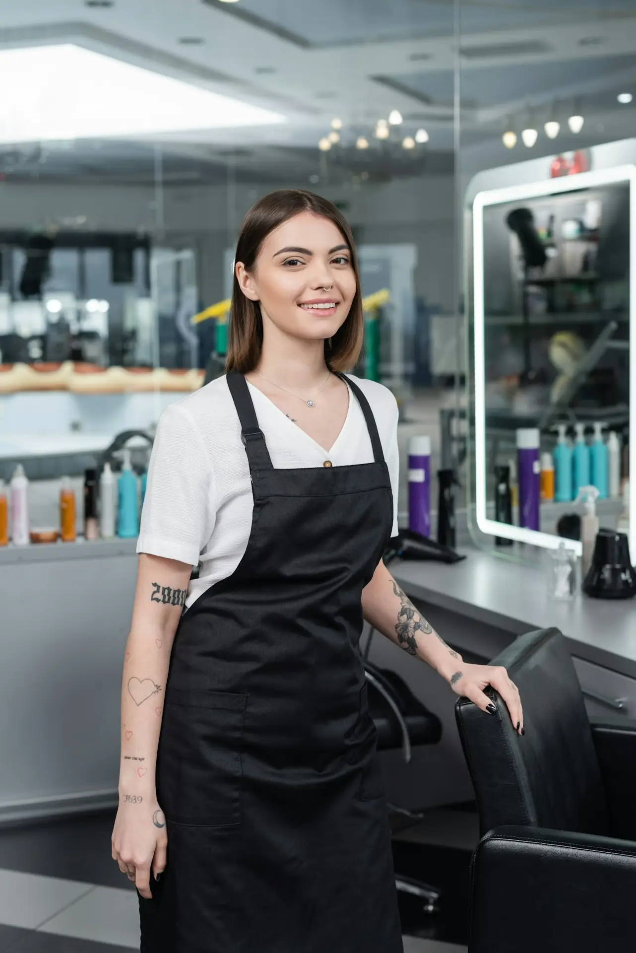 professional-headshots-tattooed-beauty-worker-in-apron-looking-at-camera-in-beauty-salon-.jpg