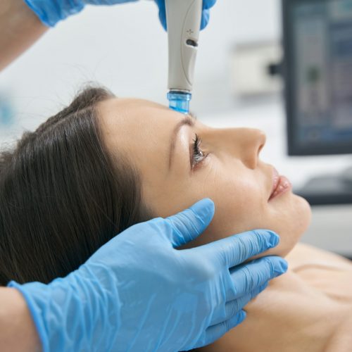 Woman having hydrafacial skincare procedure in cosmetology clinic